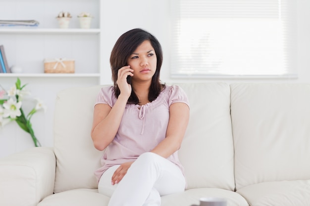 Femme assise sur un canapé tenant un téléphone