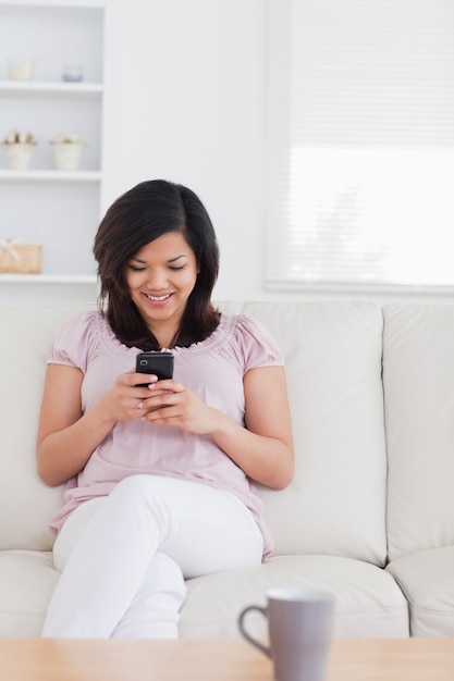 Femme assise sur un canapé et tenant un téléphone