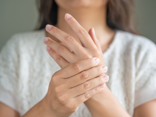 Une femme assise sur un canapé tient son poignet. blessure à la main