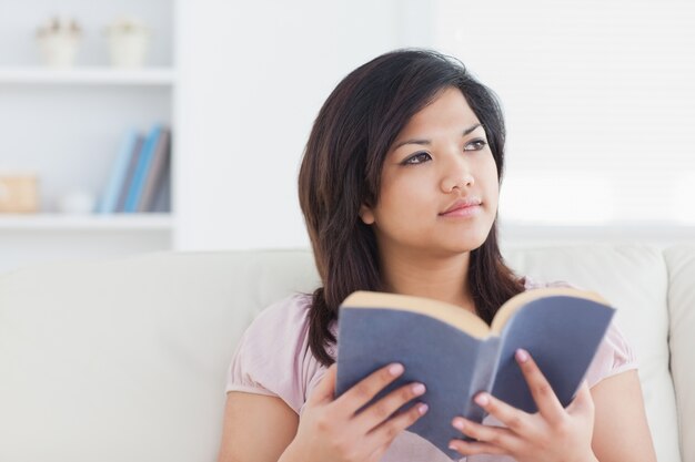 Femme assise sur un canapé tout en tenant un livre