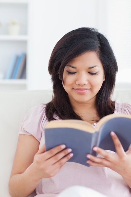 Femme assise sur un canapé en train de lire un livre