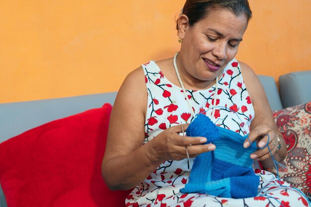 Femme assise sur le canapé et tricot