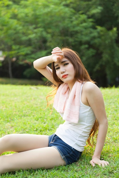 Une femme assise sur un champ dans un parc.