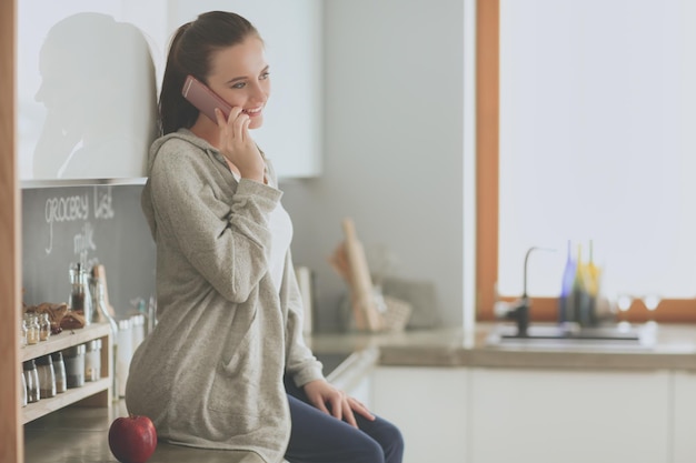 Une femme assise sur un comptoir parle au téléphone.