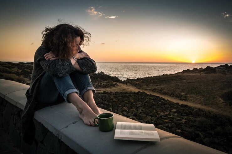 Photo une femme assise à côté d'une tasse de café et d'un livre sur la terrasse du bâtiment contre le ciel