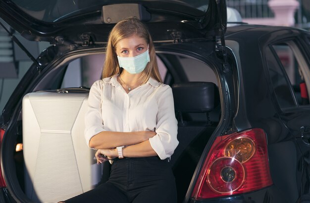 femme assise à côté de voiture avec masque