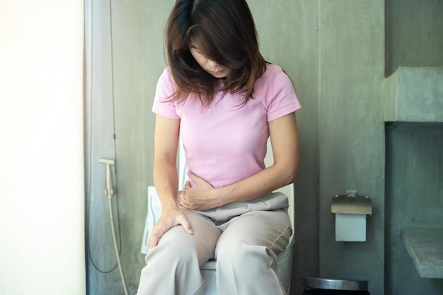 Femme assise sur la cuvette des toilettes diarrhée période de constipation infection maux de ventre abdominaux cystite Assurance et concept médical