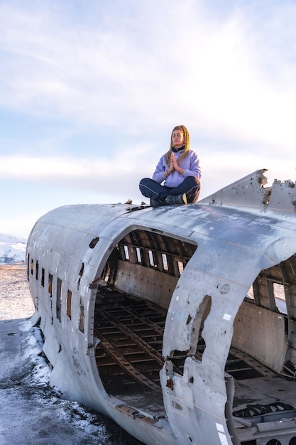 Une femme assise dans l'avion de Solheimasandur se concentre sur la méditation en Islande