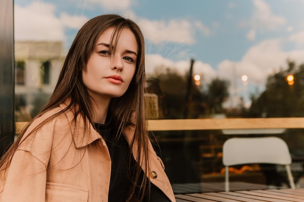 Une femme assise dans un café porte une veste marron et une chemise noire