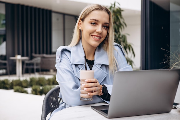 Femme assise dans un café travaillant sur un ordinateur portable et buvant du café