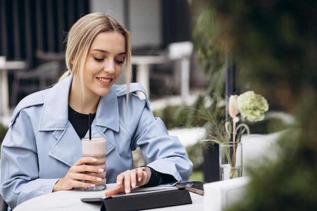 Femme assise dans un café travaillant sur un ordinateur portable et buvant du café