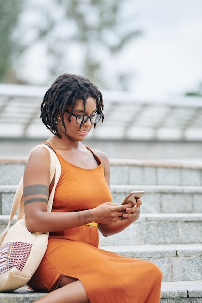 Femme assise dans les escaliers avec téléphone