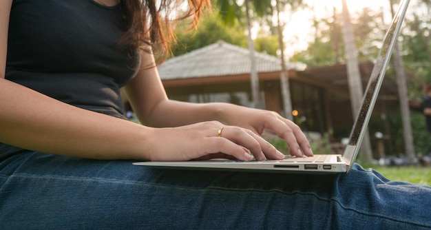 Femme assise dans un parc sur l'herbe verte avec un ordinateur portable étudiant étudiant à l'extérieur Copiez l'espace pour le texte