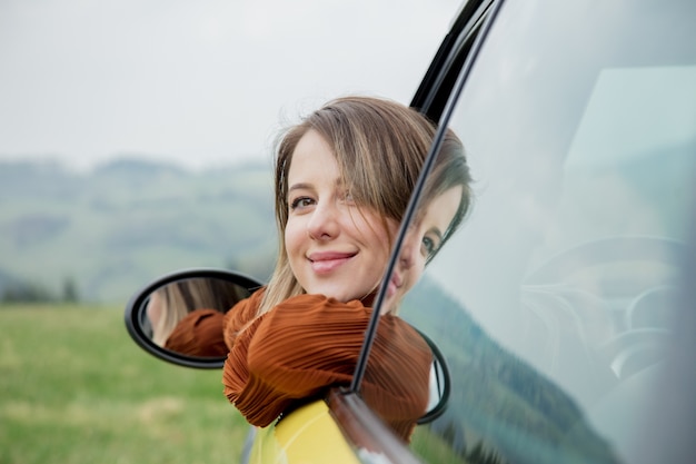 Femme assise dans une petite voiture sur une place de conducteur. Situé dans une montagne.