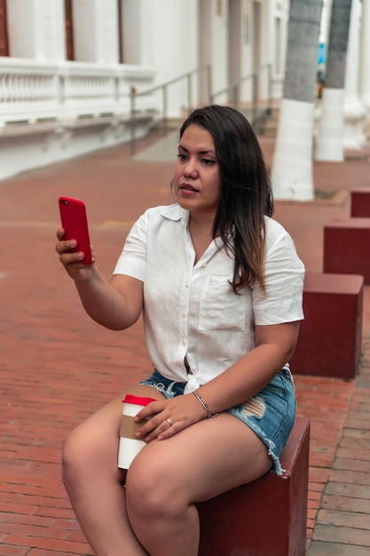 Femme assise dans la rue l'après-midi prenant un selfie