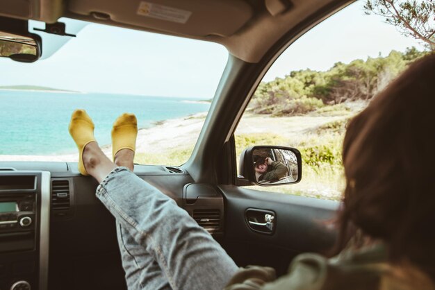 Femme assise dans une voiture regardant la réflexion de la mer dans un miroir