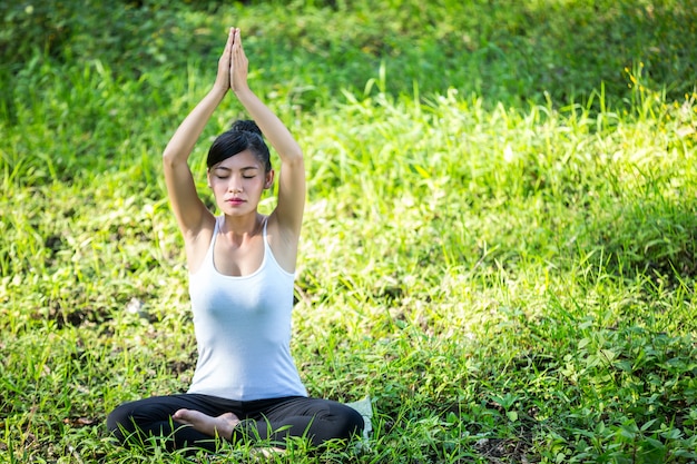 Femme assise dans le yoga dans la pelouse - se détendre dans la nature.female bonheur.