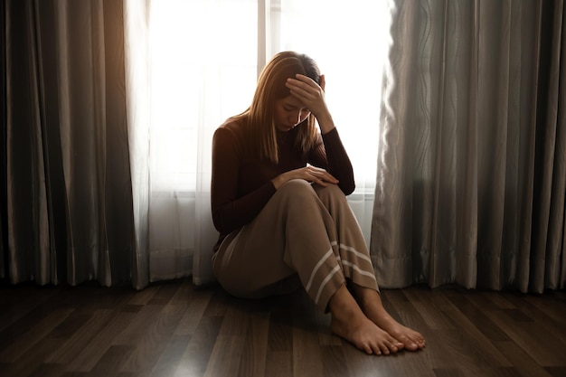 Femme assise Dépression Debout près de la fenêtre et de l'anxiété Copier l'espace xA