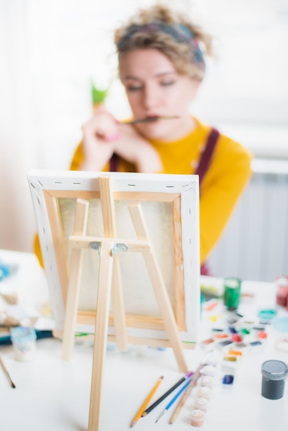 Femme assise devant un tableau et peinture au pinceau sur toile à la maison