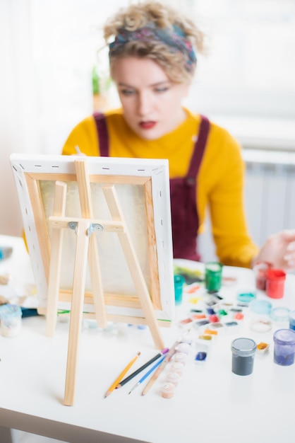 Femme assise devant un tableau et peinture au pinceau sur toile à la maison