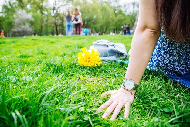 Femme assise sur l'herbe dans le parc de la ville avec des fleurs jaunes