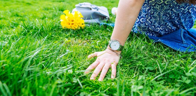 Femme assise sur l'herbe dans le parc de la ville avec des fleurs jaunes