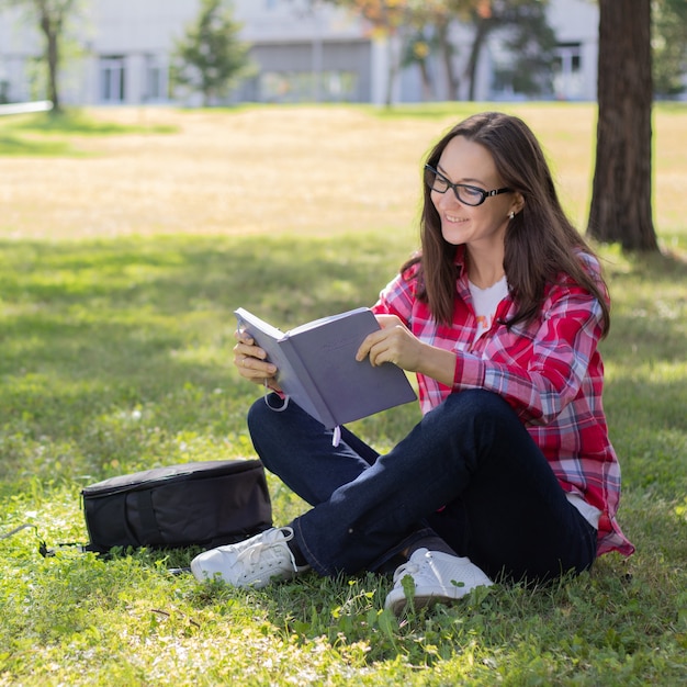 femme assise sur l'herbe et livre de lecture