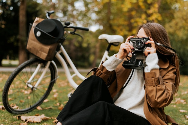 Femme assise sur l'herbe et prendre des photos