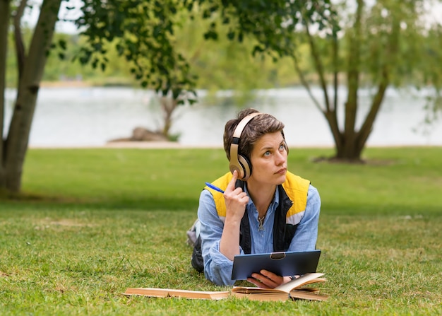 femme assise sur l'herbe verte et étudier en ligne