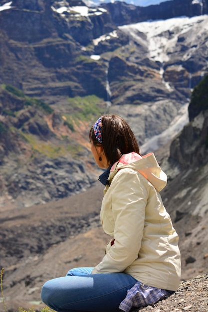 Une femme assise les jambes croisées sur la montagne.