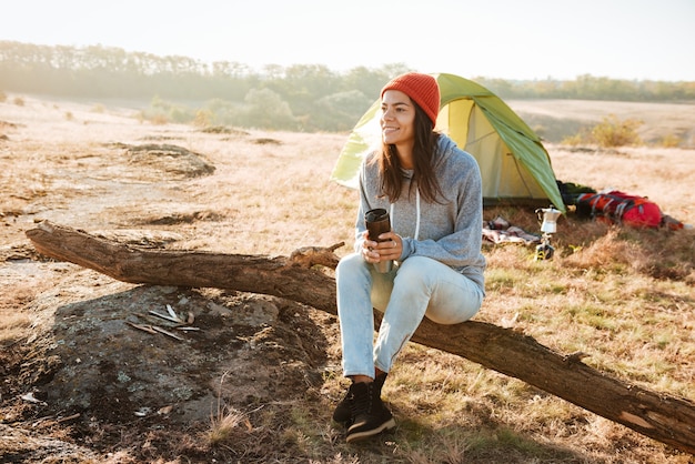 Femme assise sur le journal près de la tente