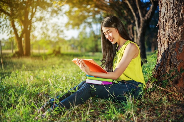 femme assise et lisant un livre dans le parc