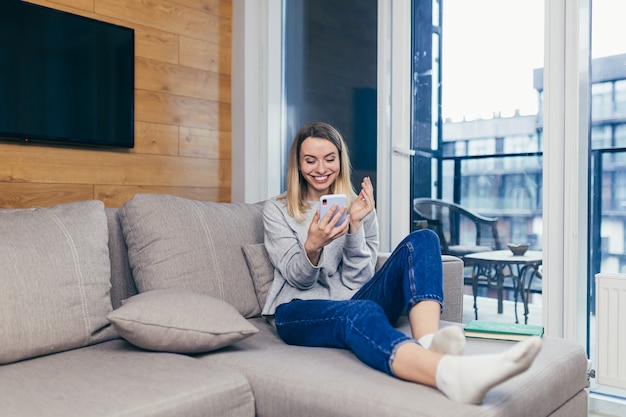 femme assise à la maison sur le canapé et utilise un téléphone portable au repos du travail