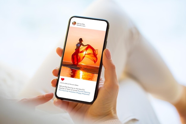 Femme assise à la maison et regardant la photo de quelqu'un sur son téléphone portable