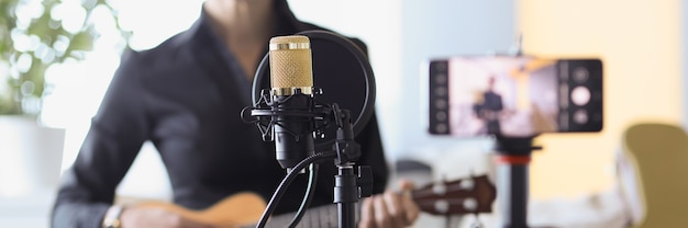 Femme assise avec microphone et tenant un ukulélé devant la caméra en gros plan sur les blogs indépendants