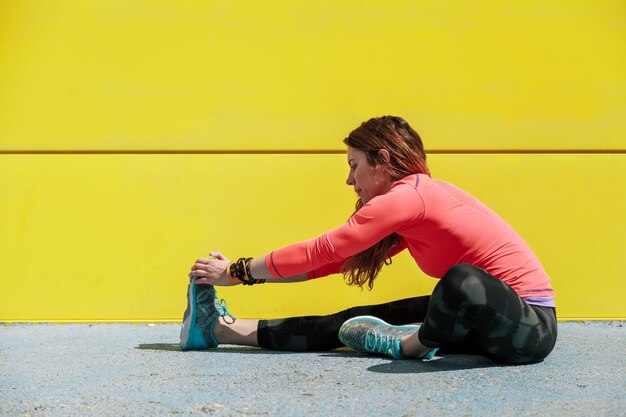 Photo une femme assise sur un mur jaune.