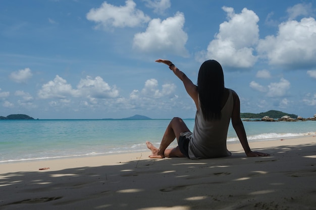 Photo une femme assise sur la plage contre le ciel