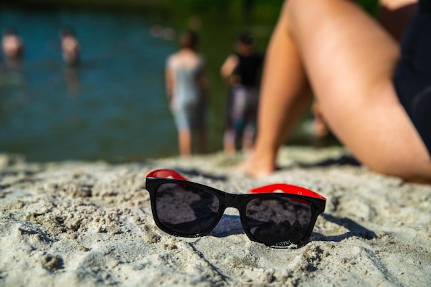 Femme assise sur la plage avec des lunettes de soleil bouchent l'heure d'été