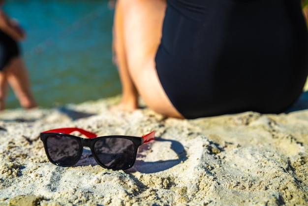 Femme assise à la plage avec des lunettes de soleil en plein été