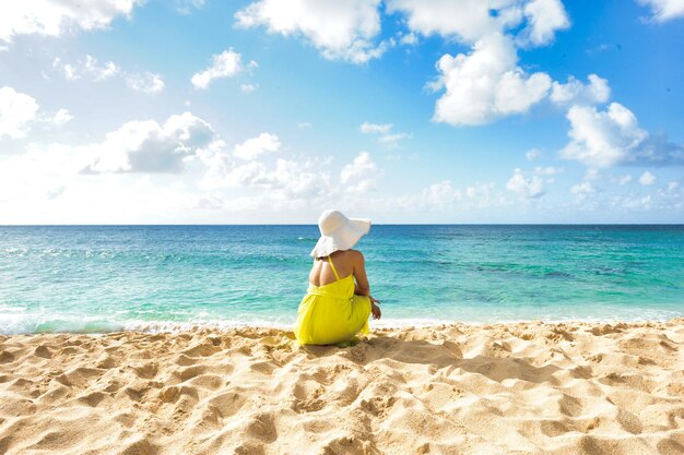 Femme assise sur la plage en regardant l'océan