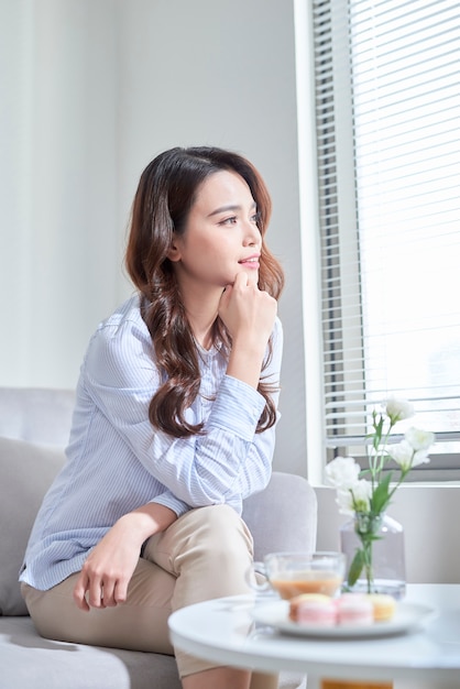 Femme assise sur le rebord de la fenêtre, regardant par la fenêtre