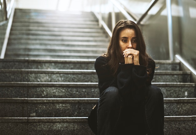 Photo femme assise regarde inquiet dans l'escalier