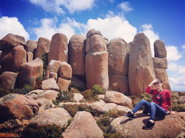 Photo une femme assise sur un rocher contre le ciel