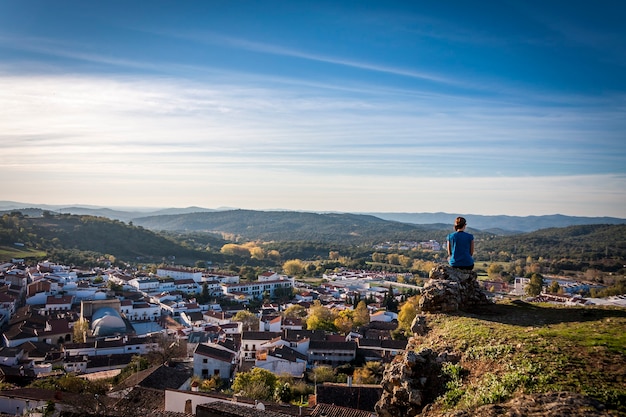 Femme assise sur un rocher en regardant une ville