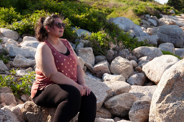 Photo une femme assise sur un rocher