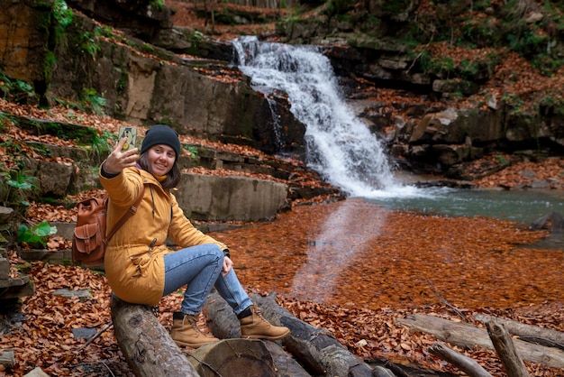 Femme assise sur le rondin regardant la saison d'automne de cascade