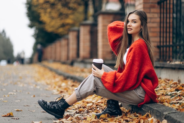 Femme assise sur la route et buvant en automne