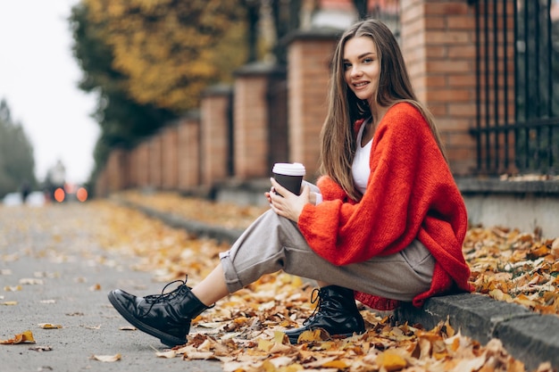 Femme assise sur la route et buvant en automne