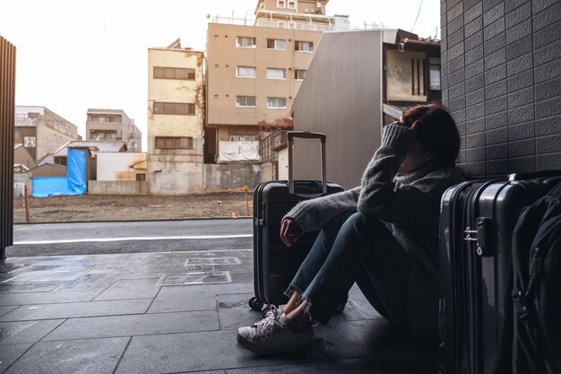 Une femme assise avec un sentiment de tristesse en voyageant avec beaucoup de bagages sur le sol