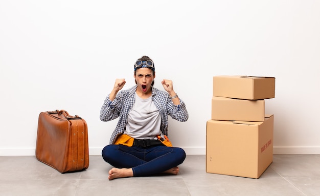 Femme assise sur le sol à côté des bagages et des boîtes en carton. Concept en mouvement